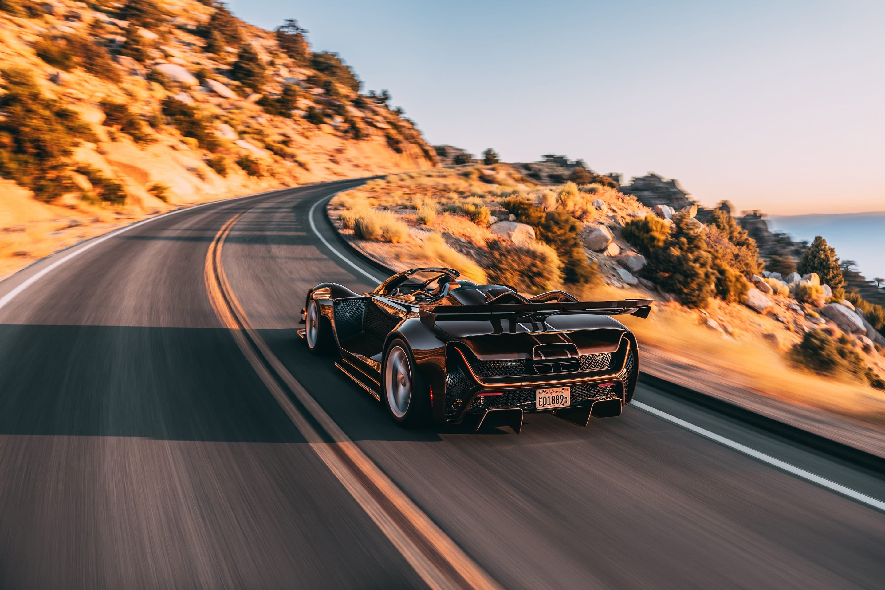 Czinger 21C Spyder, roof off, on a mountain road at golden hour