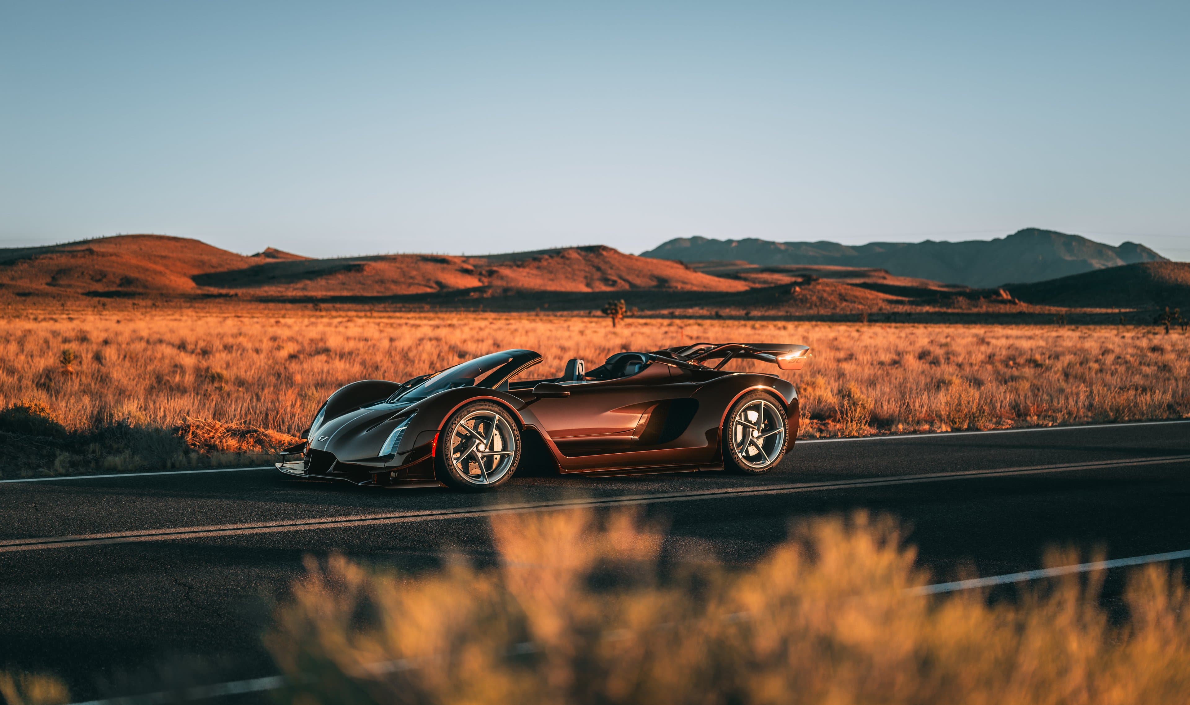 Czinger 21C Spyder — dark red, parked roadside in the desert at golden hour